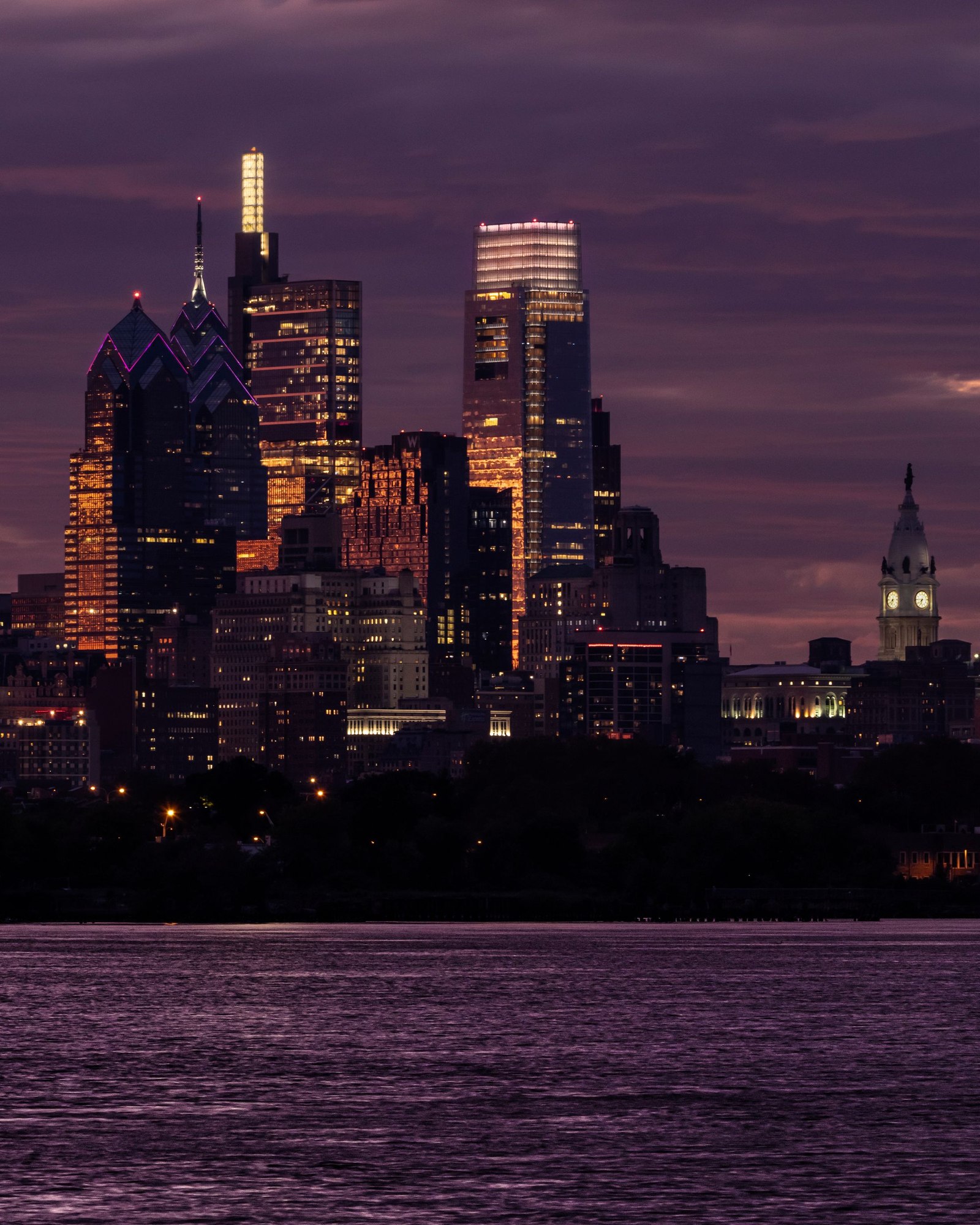 Philadelphia skyline illuminated across the river at dusk