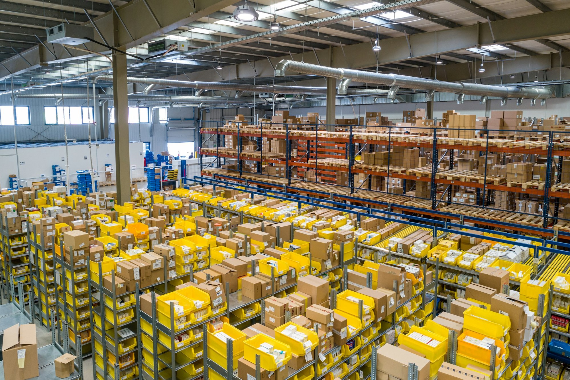 Rows of yellow picking bins and cardboard boxes inside a warehouse
